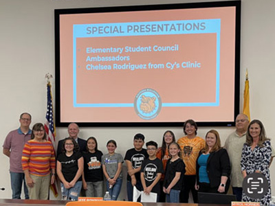 Artesia Public Schools Board of Education. Adults and children below a screen that reads: Special Presentations Elementary Student Council Ambassadors Chelsea Rodriguez from Cy's Clinic